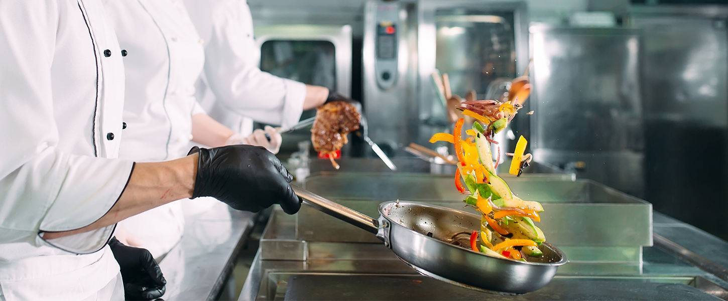 Chefs frying food in commercial kitchen